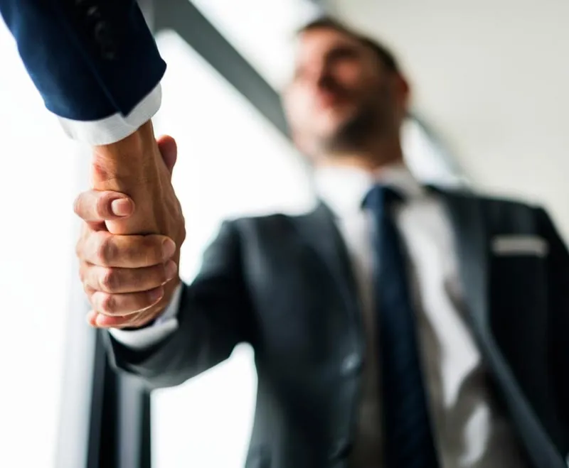 Executivos apertando as mãos como forma de cumprimento.