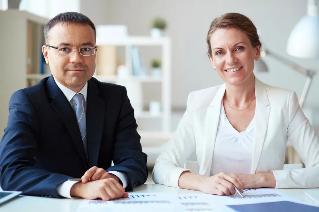 Casal de executivos de meia idade, um homem e uma mulher, analisando dados contábeis do escritório.