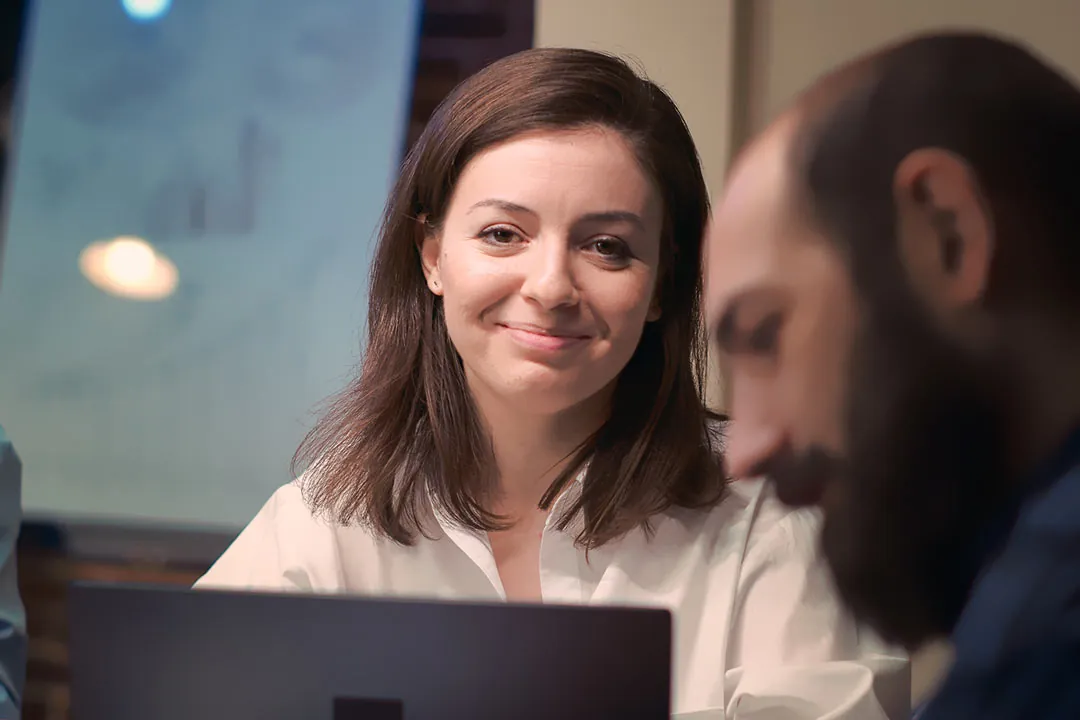 Mujer de negocios sonriendo sutilmente delante de un portátil