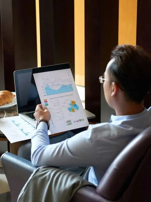 Executivo de costas em frente a um notebook, analisando gráficos contábeis da empresa
