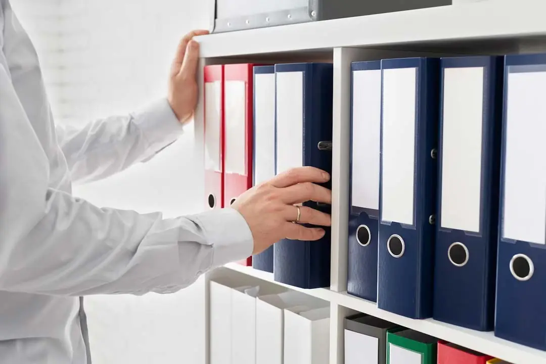 Las manos de un ejecutivo recogiendo una carpeta de un archivador de oficina