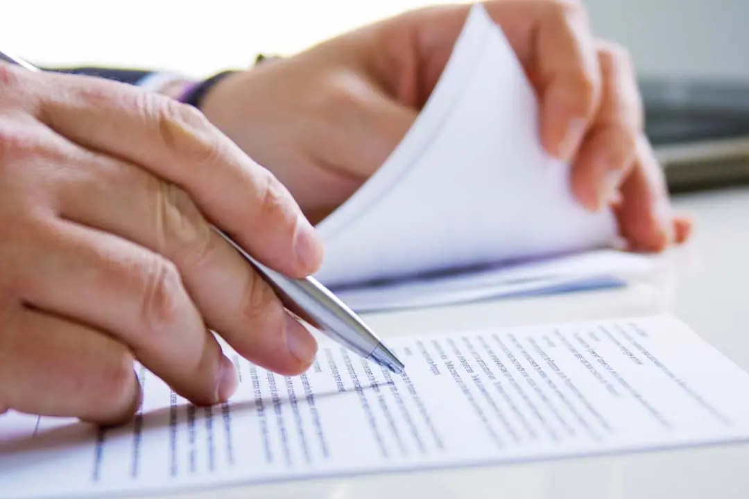 An executive's hands analyzing and scoring a document on a white table