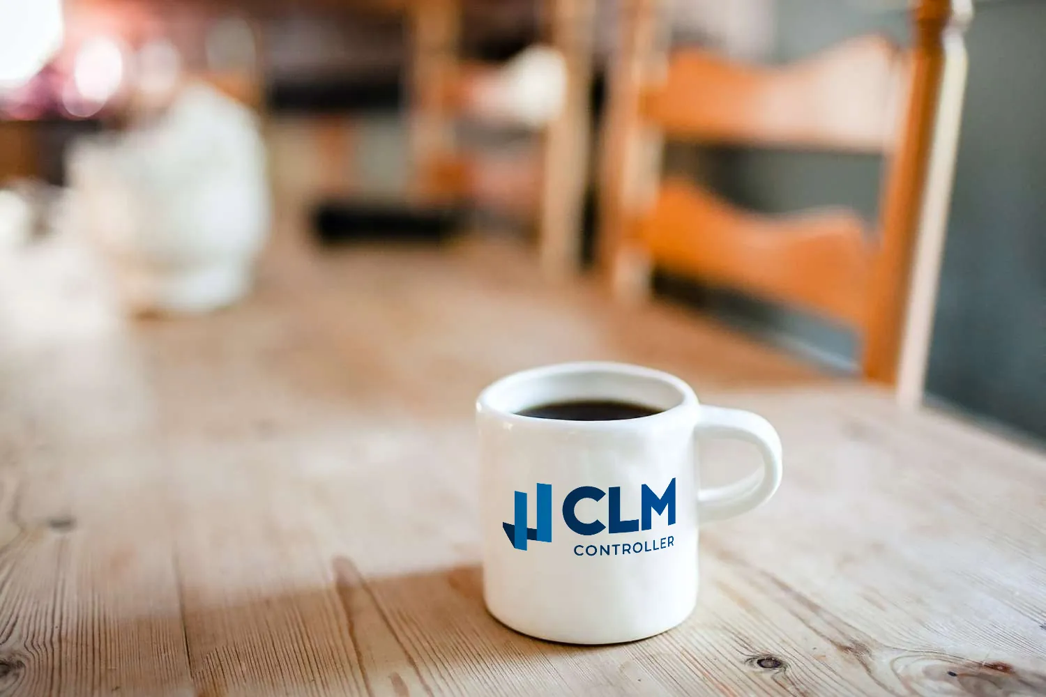 Xícara de café em cerâmica branca com logo da CLM Controller em cima de uma mesa no escritório