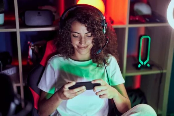 young-beautiful-hispanic-woman-streamer-playing-videogame-using-smartphone-in-game-room