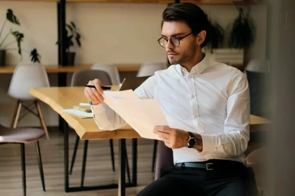 young-serious-entrepreneur-in-oculars-working-thoughtfully-with-papers-in-the-modern-office