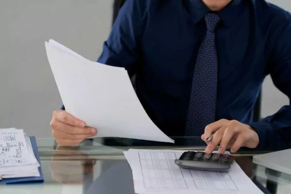 man holding sheet of paper sitting at desk in office