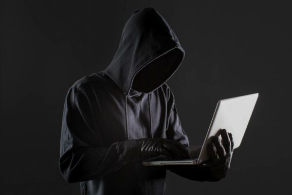 lateral-homem-hacker-com-luvas-laptop