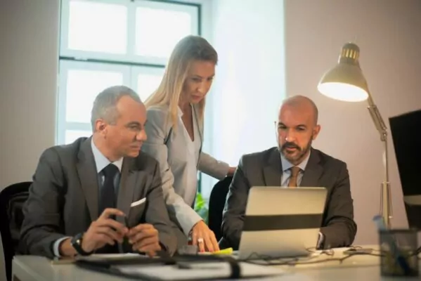 portrait managers discussing business matters two confident men women workflow looking at computer