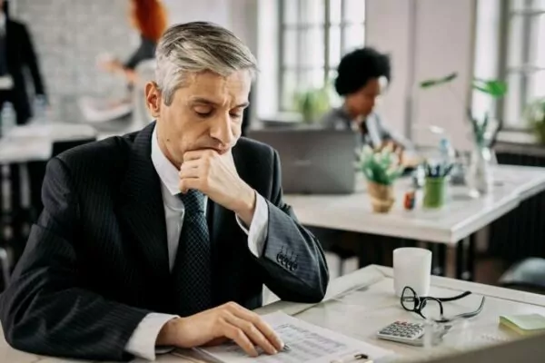 thoughtful-entrepreneur-sitting-at-the-office-going-through-financial-reports