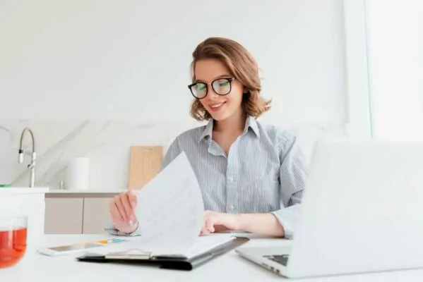 Cheerful bespectacled woman reading new contract at work