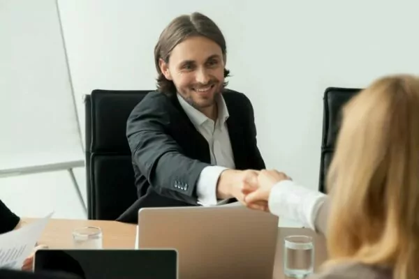 sorrindo-empresário-terno-aperto de mão-reunião-de-grupo-parceira-feminina