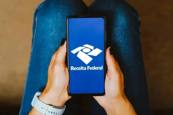 intimação Receita Federal: pessoa com o celular na mão abrindo pagina da receita